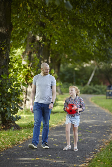 Dad and daughter walking through the park