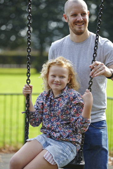 Dad pushing daughter on swing