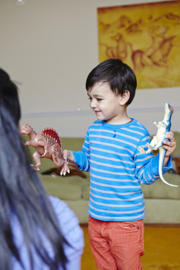 Mum and boy playing with toy dinosaurs