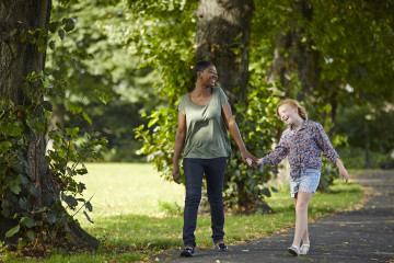 Mum and girl walking in park