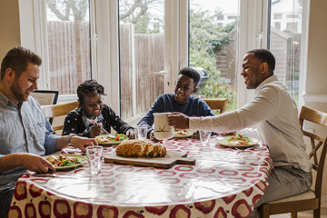 Same sex couple with son and daughter eating at the table