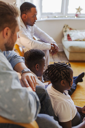 Same sex couple with son and daughter watching tv