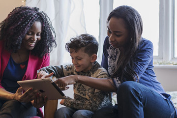 Same sex couple with son play on tablet