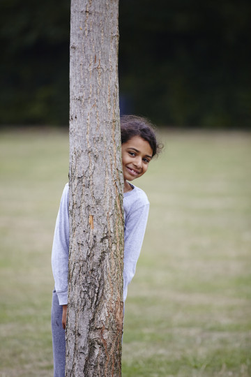 Girl behind tree trunk