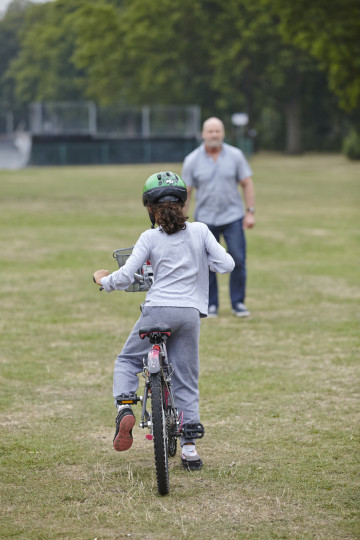 Dad encourages daughter on bike