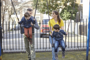 Mum and Dad pushing children on swings